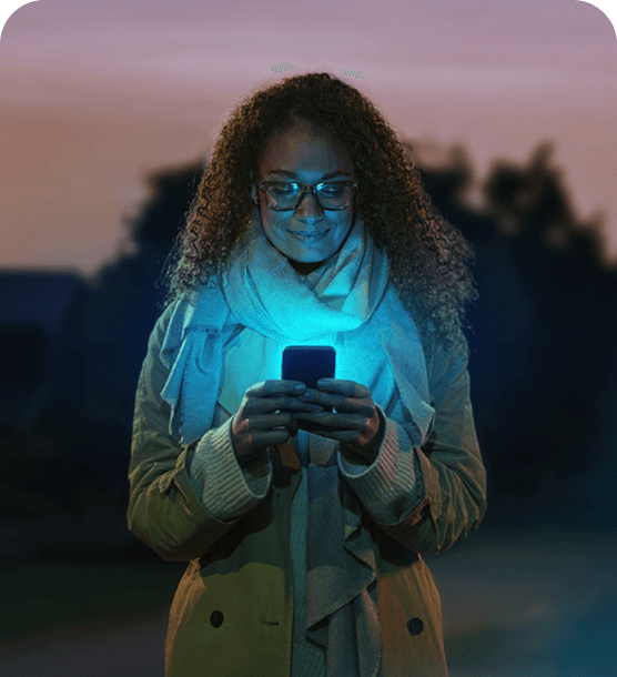 A woman looking at her phone at night